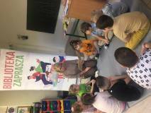 Pani bibliotekarka z przedszkolakami oglądającymi książki